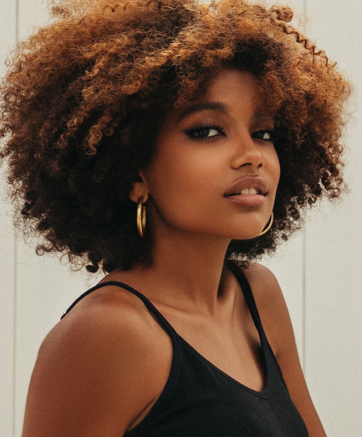 Person with curly hair wearing hoop earrings.