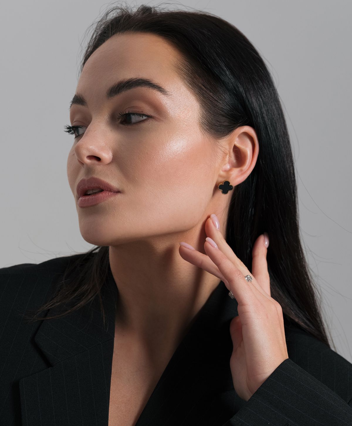 Woman in blazer showcasing elegant jewelry.