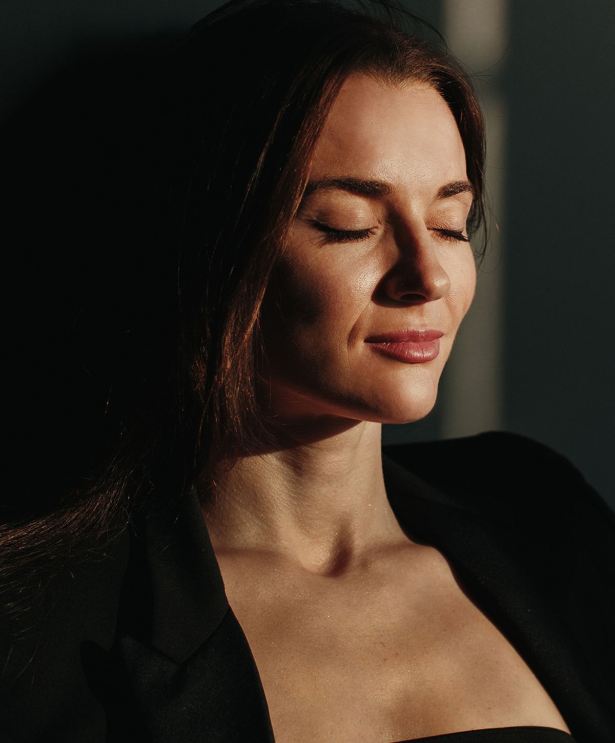 Woman with closed eyes in soft lighting.