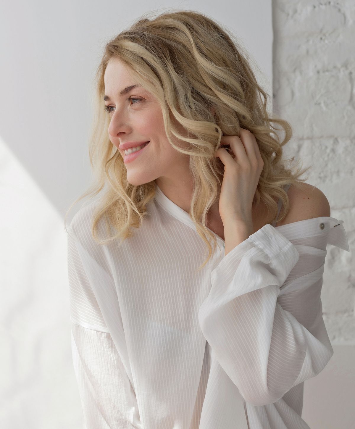 Smiling woman with blonde hair in white top.