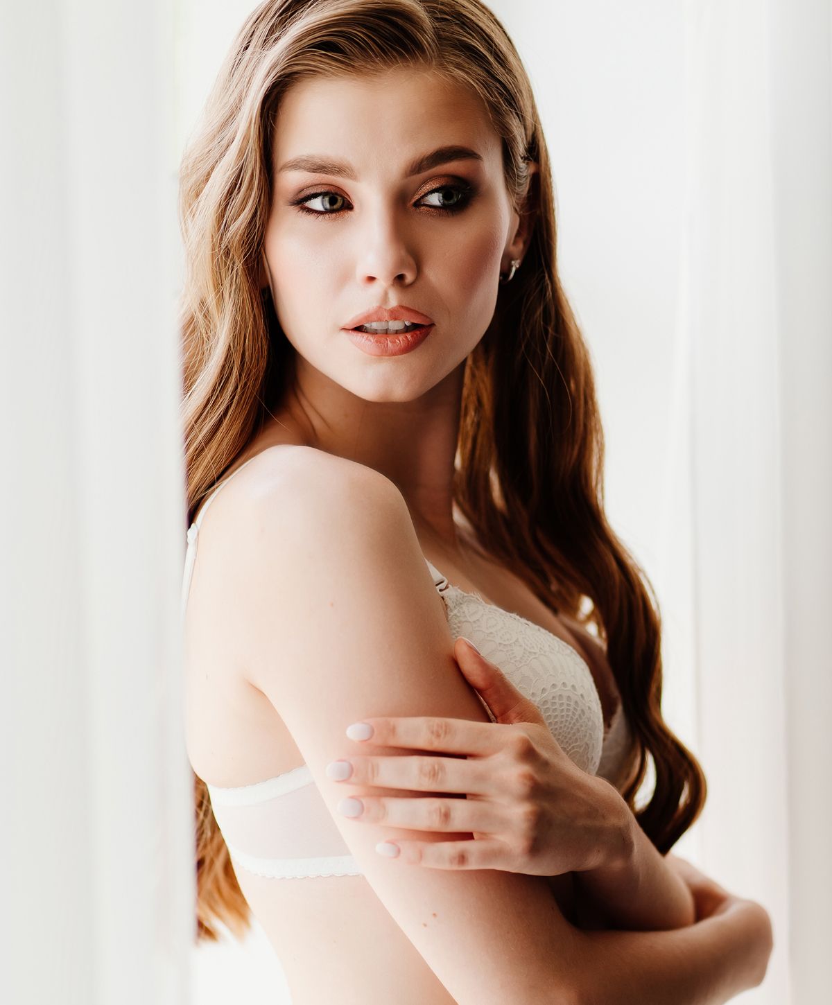 Young woman in lingerie by window.