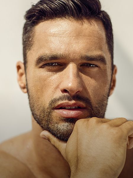 Man with beard and stylish hair, smiling softly.