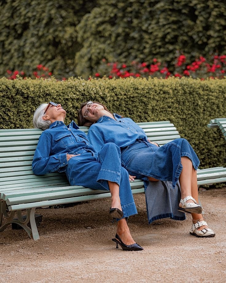 Two women laughing on a bench outdoors.