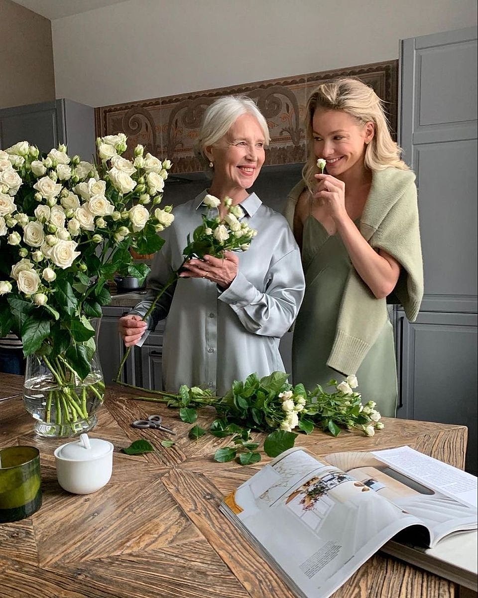 Two women arranging white roses together.