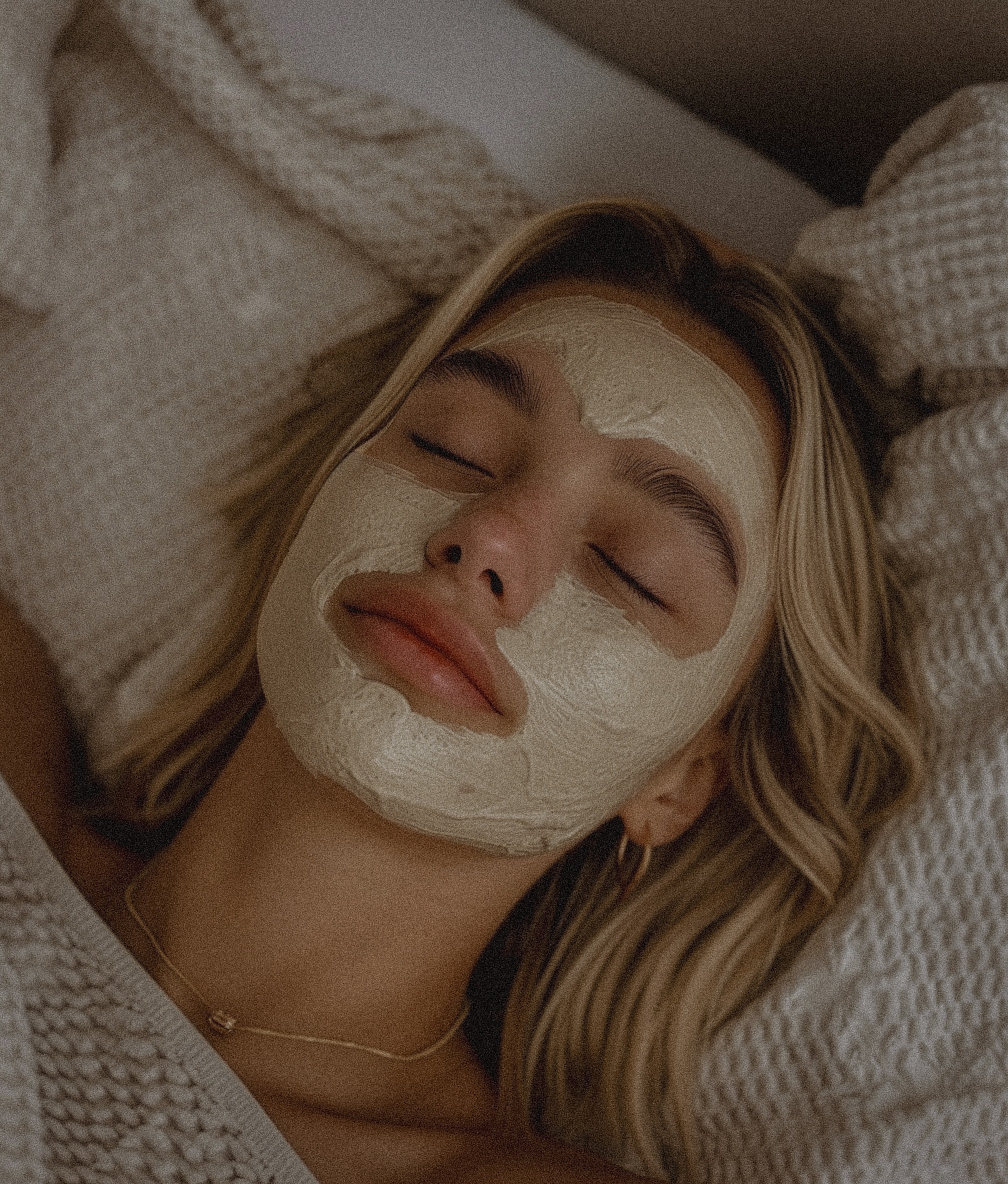 Woman relaxing with a facial mask in bed.