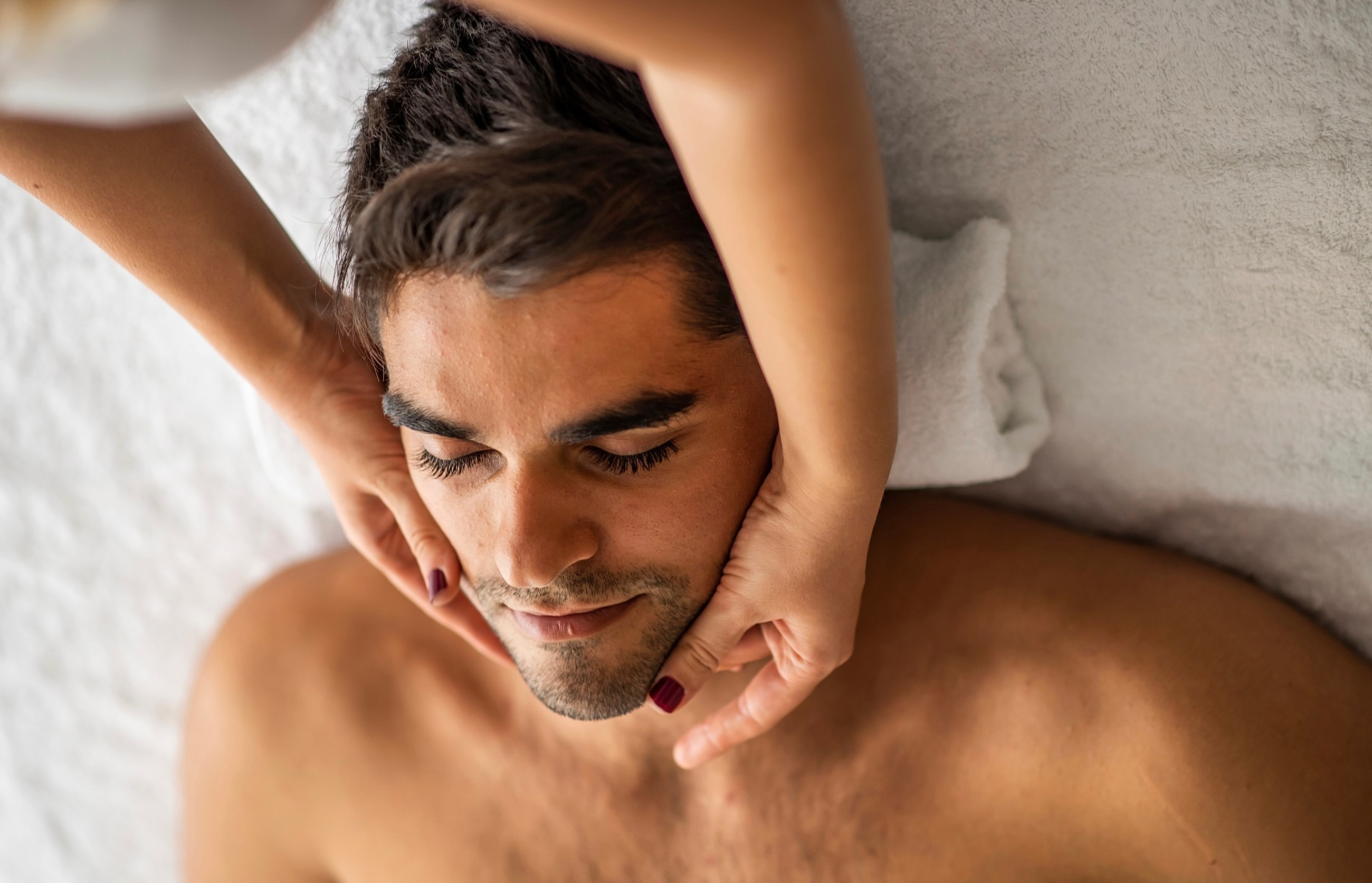 Smiling man with towel in modern bathroom setting.
