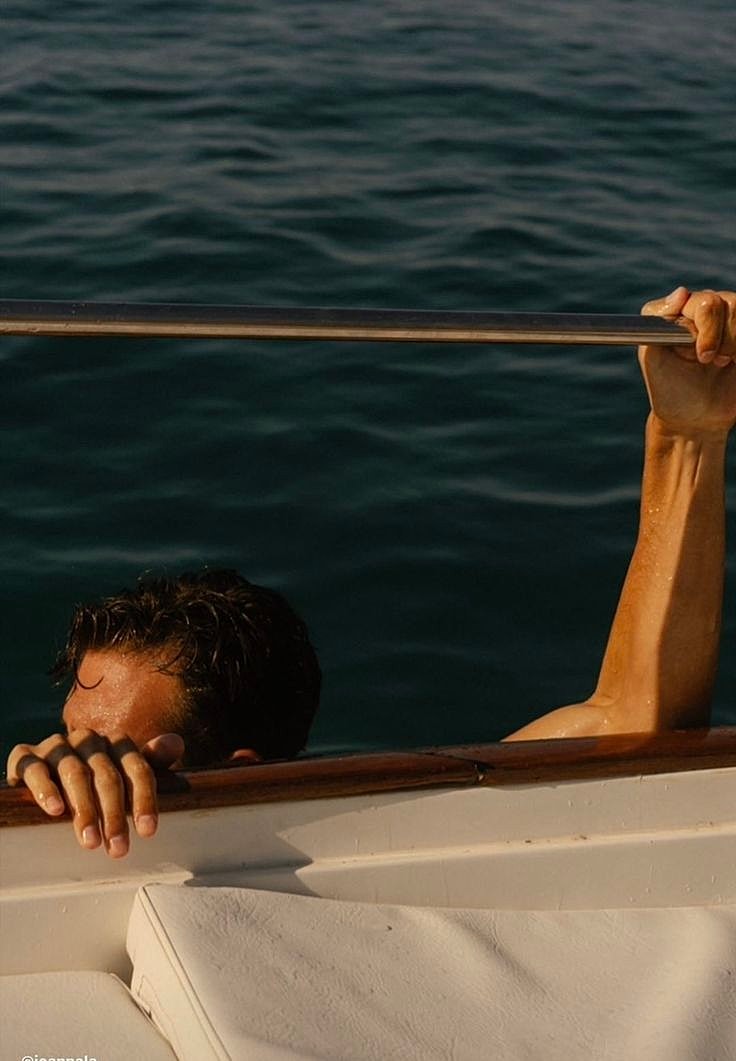 Person holding onto boat railing over water.