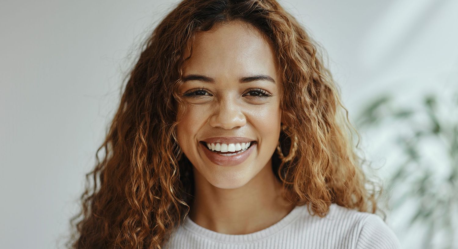 Smiling woman with curly hair in natural light.