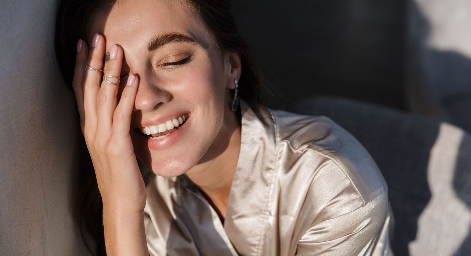 Smiling woman with hand covering her face.