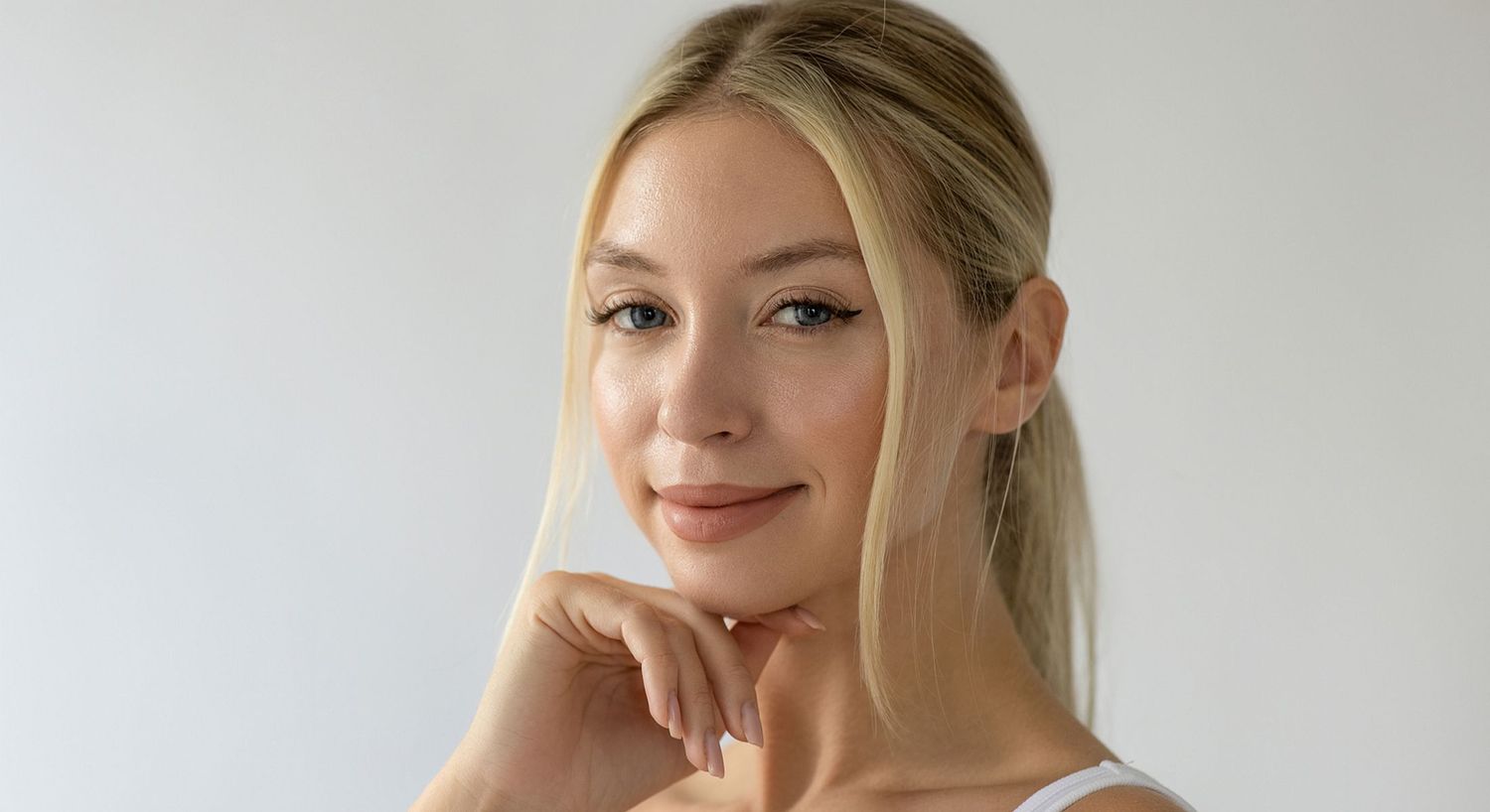 Young woman smiling with hand on chin.