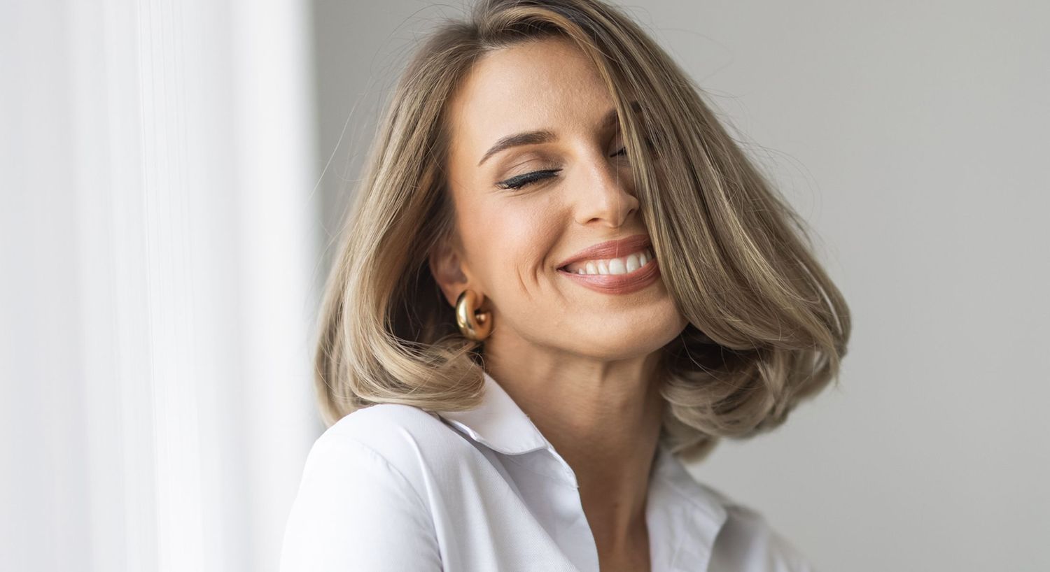 Smiling woman with flowing blonde hair indoors.