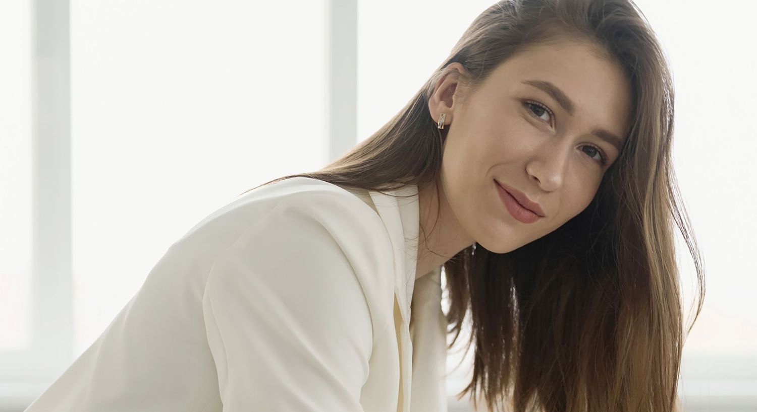 Woman smiling in a bright, minimalist setting.